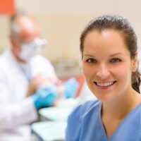 Female dental assistant smiling at stomatology office dentist with patient